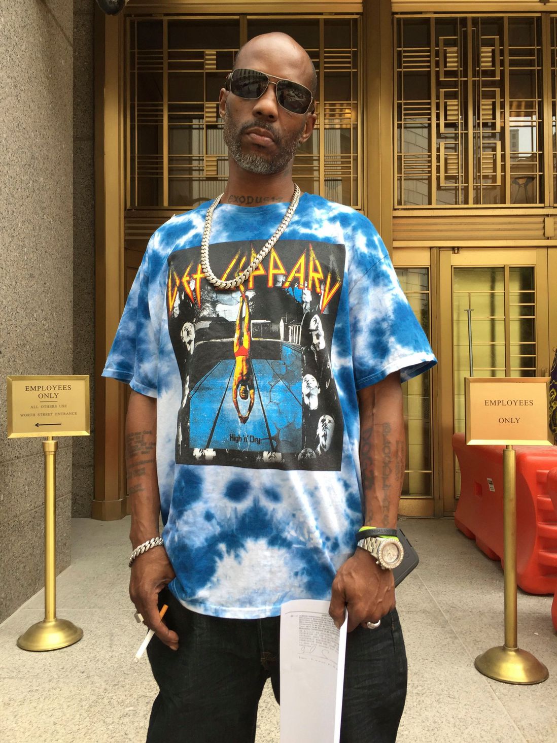 DMX, wearing a Def Leppard shirt, stands outside the court